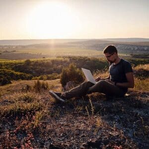 Young man sitting with a laptop out in nature