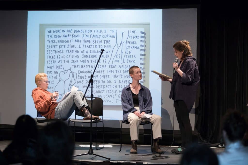 A group of people on a stage in front of a screen with a poem projected on it
