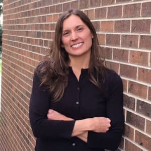 Lexi Widman standing against a brick wall.