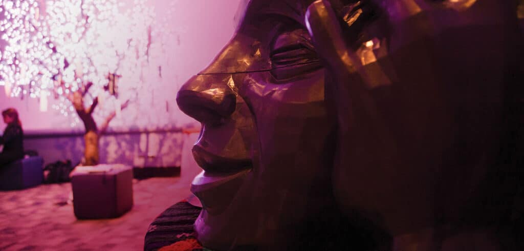 A sculpture of a face dimly illuminated by violet light