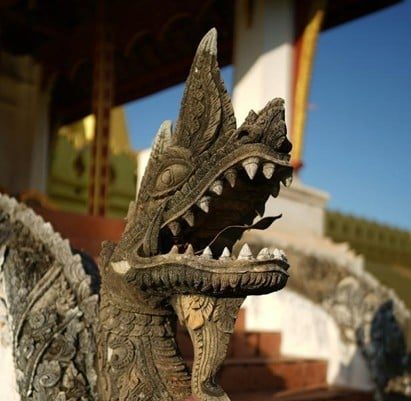 Ornate carved temple guardian statue with intricate details in bright sunlight.