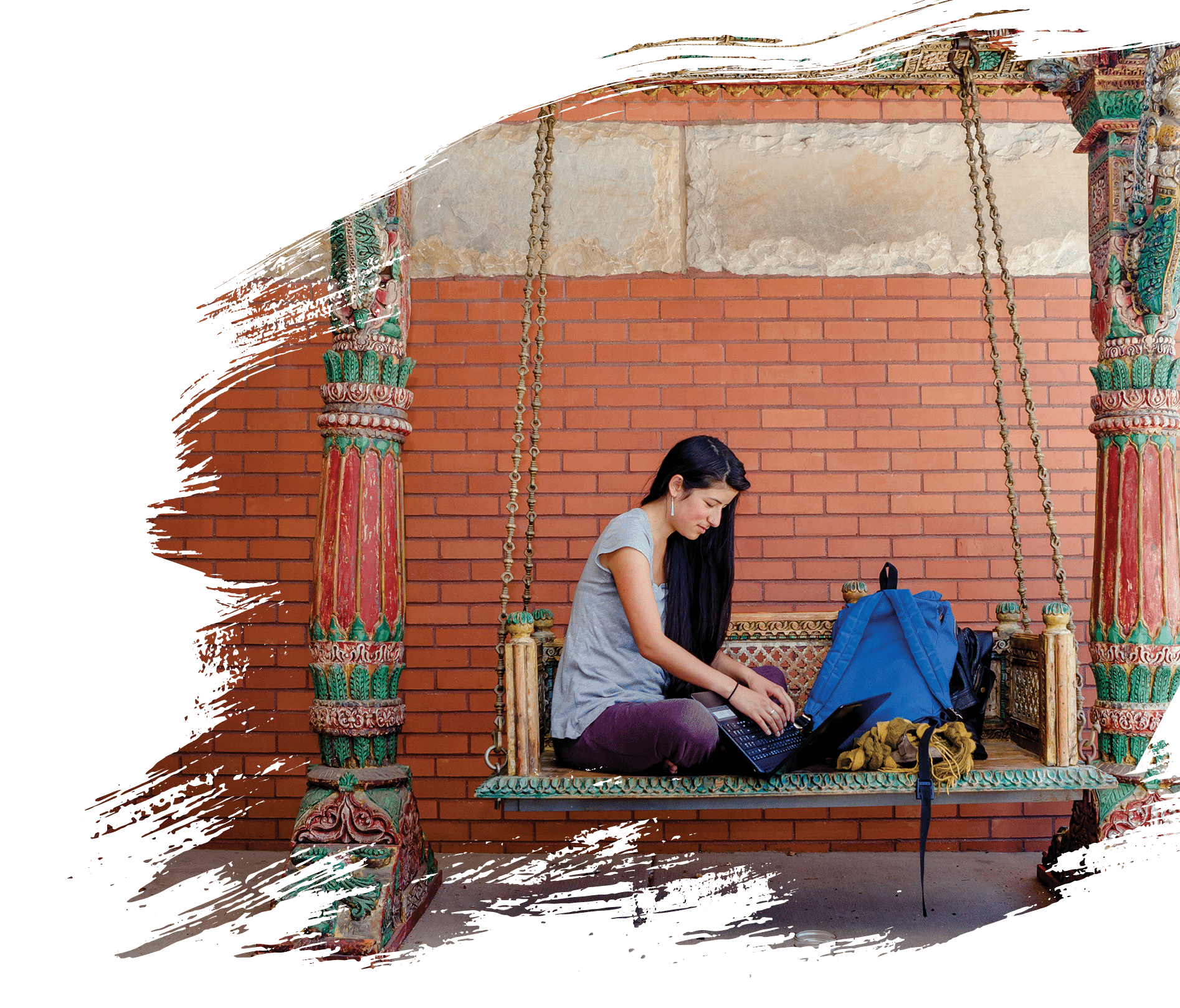 A woman sitting on a swing with a laptop
