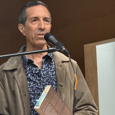 Vincent Katz holding a book at a microphone