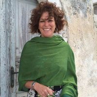 Kendra Sandoval wearing a green shawl standing in front of a door