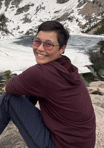 A woman sitting on a rock with snow and a lake in the background